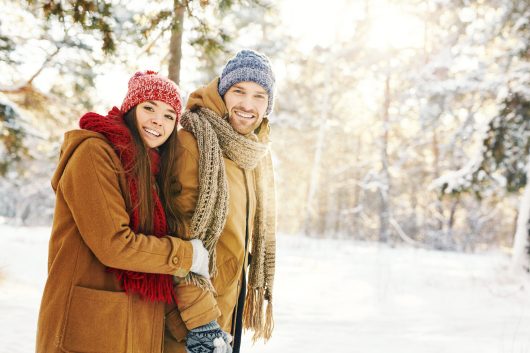 Happy couple in winterwear taking walk in forest